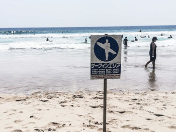 Information sign on beach against clear sky