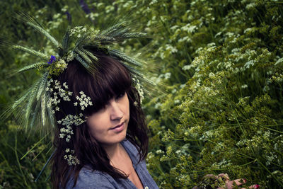 Portrait of woman swearing flowers while standing by plants