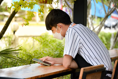 Side view of young man sitting on table