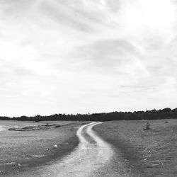 Road amidst field against sky