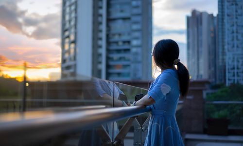 Side view of woman looking at city buildings