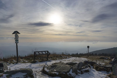 Snow covered land against sky during sunset