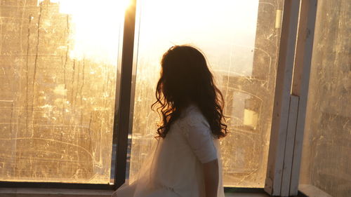 Rear view of woman looking through window