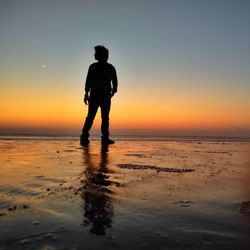 Silhouette man standing on beach against sky during sunset