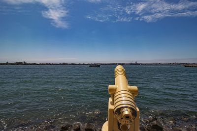 Close-up of metal structure by sea against sky