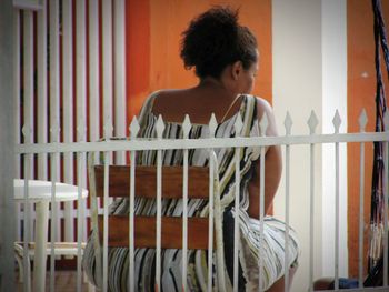 Full length of shirtless man sitting on railing