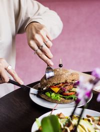 Midsection of woman having burger at table