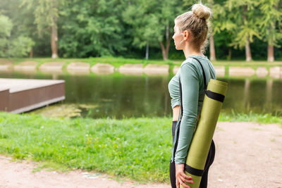 A slender woman in the park in summer, with a green gym mat behind her back
