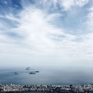 Aerial view of city by sea against sky