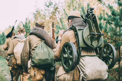 Rear view of army soldiers with weapons walking in forest