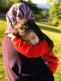 Woman carrying daughter at park