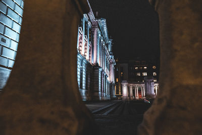 Empty road amidst buildings against sky at night