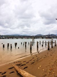 Wooden posts on beach against sky