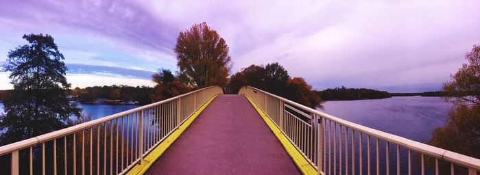 Footbridge over lake against sky