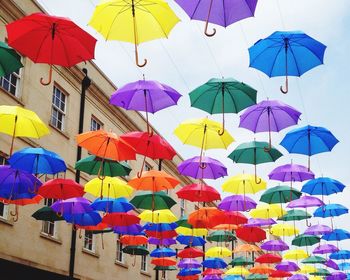 Low angle view of multi colored umbrellas hanging by building