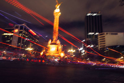 Light trails by monument in city at night