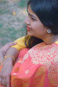 Young woman looking away while sitting outdoors