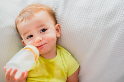 Portrait of cute baby boy drinking milk from bottle at home