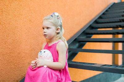 Portrait of cute girl standing against wall