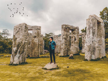 Man standing on rock against sky