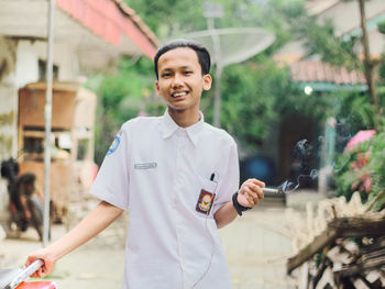 Portrait of smiling man holding while standing in city