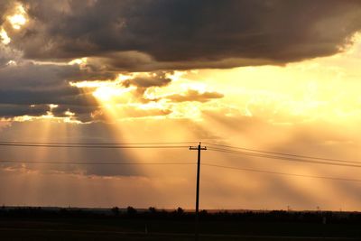 Silhouette electricity pylon against sky during sunset