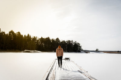 Rear view of man standing on jetty