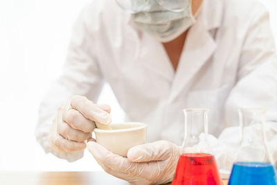 Midsection of pharmacist making medicines against white background