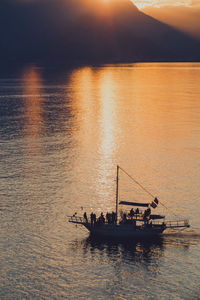 Silhouette man in boat in sea during sunset