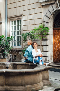 Happy friends sitting outside building