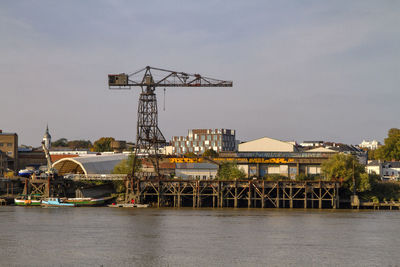 Cranes at harbor against sky