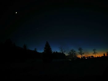 Silhouette trees against sky at night