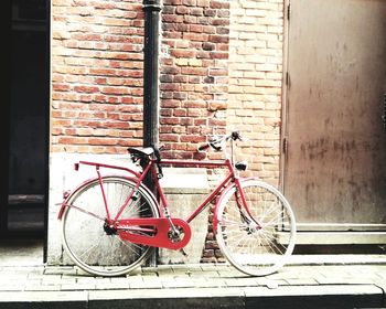 Bicycle parked against brick wall