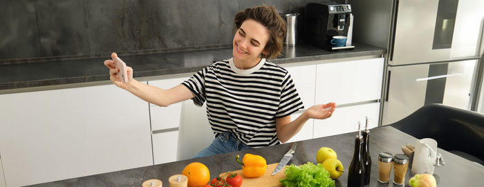 Portrait of young woman holding food at home