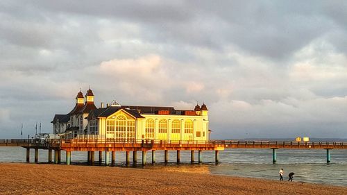 Buildings on beach against cloudy sky