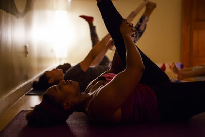 A small group of women practice stretches in a darkened room