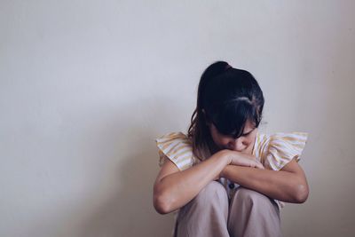 Woman holding girl against wall