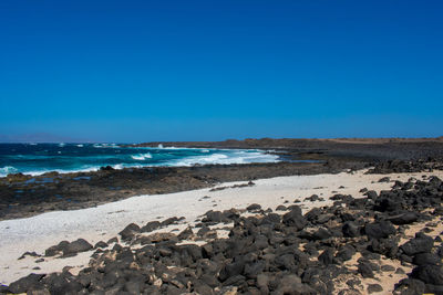 Scenic view of beach against clear blue sky