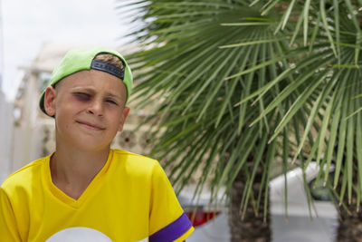 Portrait of young man standing against palm tree