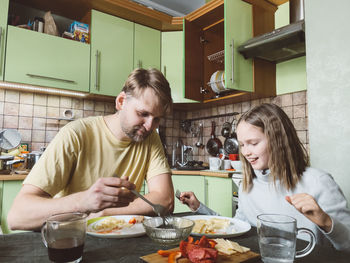 Father and daughter having food at home