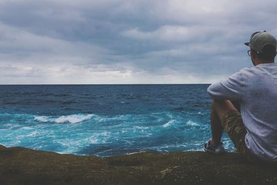 Rear view of man standing in sea against sky