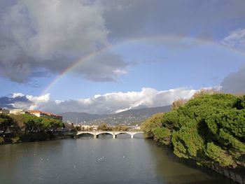 Scenic view of rainbow over river against sky