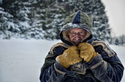 Portrait of senior man wearing warm clothing on snow covered field