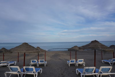 Chairs on beach against sky