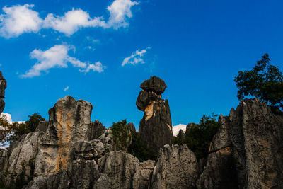 Low angle view of rocks against blue sky