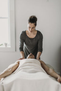 Female massage therapist treats male patient on massage table