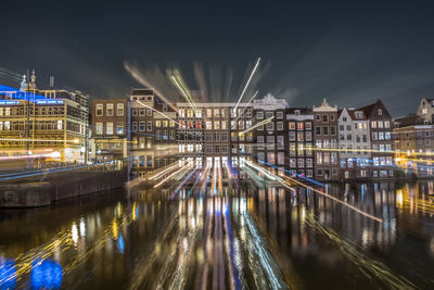 Illuminated bridge over river in city at night