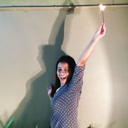 Portrait of smiling young woman standing against wall