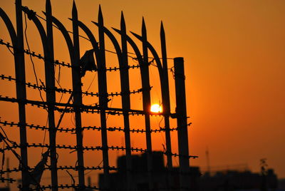 Low angle view of silhouette buildings against orange sky