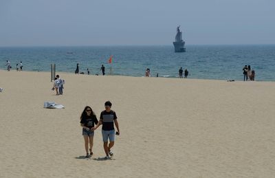 People at beach against sky